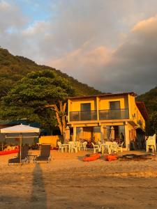 ein gelbes Haus mit Tischen und Stühlen davor in der Unterkunft Casa Sol da Ilha in Angra dos Reis