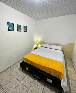 a bedroom with a large bed with a yellow blanket at Cantinho do Sol in Recife