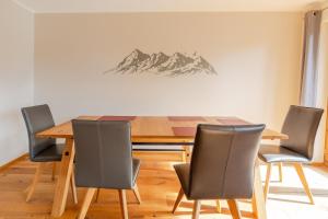 a dining room with a wooden table and chairs at Gipfelblick in Rettenberg