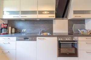 a kitchen with white cabinets and a sink at Gipfelblick in Rettenberg +8 photos