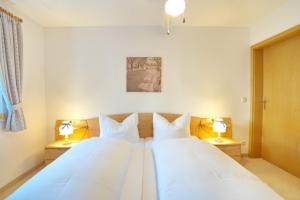 a bedroom with two white beds with two lamps at StaigAllgäublick in Sonthofen