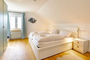 a white bedroom with a white bed and a window at Spitzkehren in Blaichach