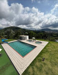 a swimming pool in the middle of a grass field at Apartamentos campestres la Divisa in Santa Rosa de Cabal
