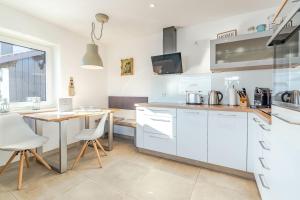 a kitchen with white cabinets and a table and chairs at Fewo Blick in die Berge in Ofterschwang