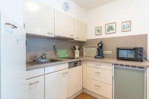 a kitchen with white cabinets and a sink and a microwave at Gipfelliebe in Bad Hindelang