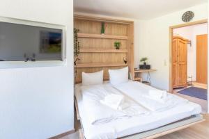 a bedroom with a white bed with a tv on a wall at Ferienwohnung Manns in Bad Hindelang