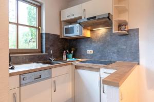a kitchen with white cabinets and a sink and a window at Bergfriede in Bad Hindelang