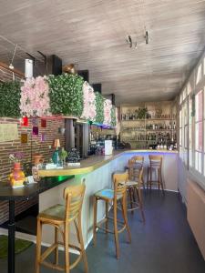 a bar in a restaurant with wooden chairs and flowers at Auberge Les Mufliers - Hôtel Les Forges in Pontenx-les-Forges