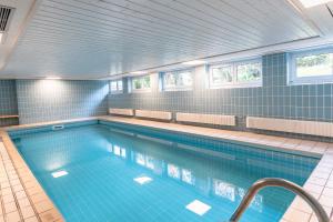 a large swimming pool with blue tile walls and windows at Ifen in Fischen