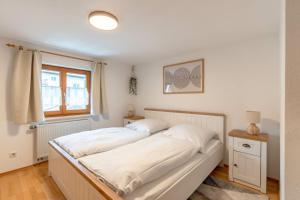 ein Schlafzimmer mit einem Bett mit weißer Bettwäsche und einem Fenster in der Unterkunft Stolz 2 in Blaichach