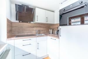 eine weiße Küche mit Spüle und Kühlschrank in der Unterkunft Stolz 2 in Blaichach