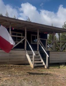 a log cabin with stairs leading to a porch at Cabañita Coyhaique in El Cerrillo
