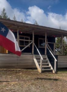 a house with a flag in front of it at Cabañita Coyhaique in El Cerrillo