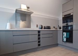 a kitchen with gray cabinets and a stove top oven at SeaBreeze - Portballintrae in Portballintrae
