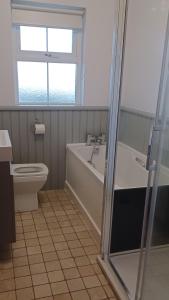 a bathroom with a tub and a toilet and a window at SeaBreeze - Portballintrae in Portballintrae +19 photos