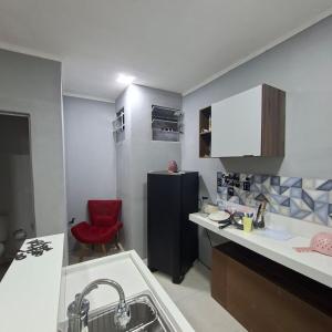 a kitchen with a refrigerator and a red chair at Espaço completo aconchegante no 2 andar in Belém