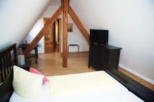a bedroom with a bed with a television and a staircase at Berne's Altstadthotel in Besigheim