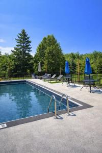 a swimming pool with two blue umbrellas next to it at Coach House Inn in Tobermory