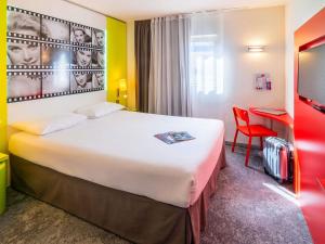 a hotel room with a large bed and a red chair at ibis Styles Cannes Le Cannet in Cannes