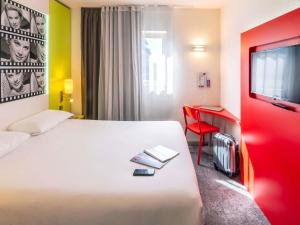 a hotel room with a large bed and a tv at ibis Styles Cannes Le Cannet in Cannes