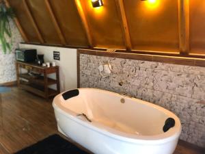 a bath tub in a bathroom with a stone wall at Chalé Dengo Dengo - Refúgio Romântico na Serra da Mantiqueira in Pindamonhangaba +33 photos