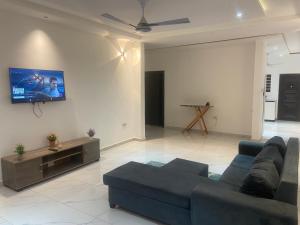 a living room with a couch and a tv on a wall at 2BR Ultra Modern Apartment in Gbawe in Gbawe