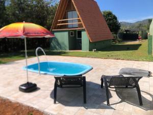 a table and two chairs and an umbrella on a patio at Chalé Dengo Dengo - Refúgio Romântico na Serra da Mantiqueira in Pindamonhangaba