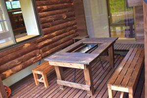 a picnic table and benches on a porch of a cabin at まるもりビレッジ in Wada