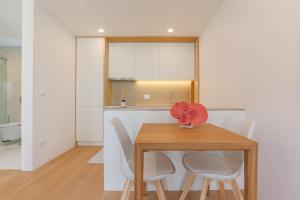 a kitchen with a wooden table and white cabinets at D'AUSE - New Modern Apt - 150m to Beach & Center in Esposende