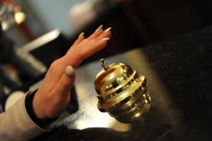a woman is reaching for a gold bell on a counter at Millenium Palace in Ohrid