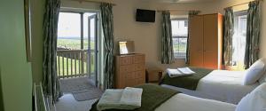 a bedroom with two beds and a balcony at SeaBreeze - Portballintrae in Portballintrae