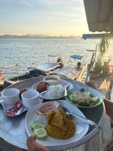 a table with a plate of food on a boat at Kaneng Homestaykohpu in Ban Klang