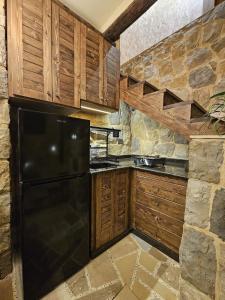 a kitchen with a black refrigerator and a stone wall at MiCastel in Ad Dawwār