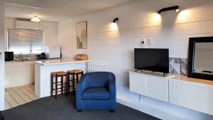 a living room with a tv and a blue chair at The Ranolf Residence in Rotorua