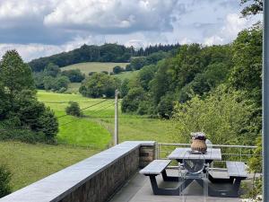 a picnic table on a balcony with a view of a field at The Sweet Escape Premium villa with pool in Theux
