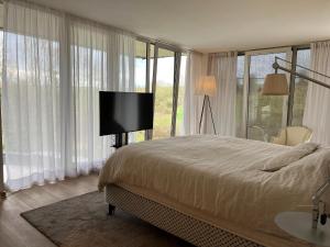 a bedroom with a bed and a flat screen tv at The Sweet Escape Premium villa with pool in Theux +32 photos