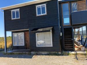 a black house with two windows and a door at Villa Lagunitas in Puerto Montt