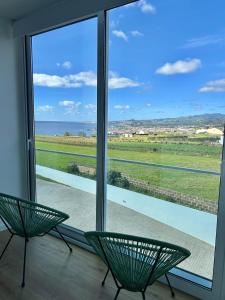 two green chairs sitting in front of a large window at Azorescape in Lagoa +50 photos