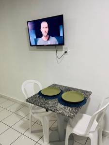a table with chairs and a tv on a wall at Aparthotel holandeses in São Luís