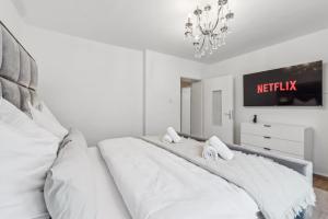 a white bed in a white bedroom with a chandelier at Design-Apartment in Rüttenscheid, Kulturlage & Top-Anbindung in Essen