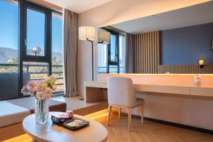 a living room with a desk and a table at Orange Crystal Hotel Dali Erhai Park in Dali