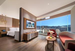 a hotel room with a bed and a couch at Orange Crystal Hotel Dali Erhai Park in Dali