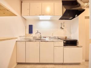 a kitchen with white cabinets and a sink at Southern Gate HIVE in Ishigaki Island +50 photos