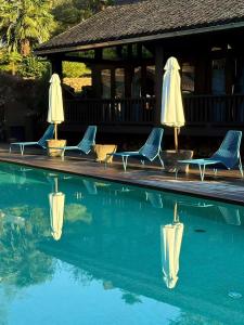 four chairs and umbrellas next to a swimming pool at Mocun Resort in Deqing