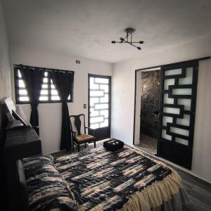 a bedroom with a bed and a chair and windows at Hospedaje Don Juve in Atlixco