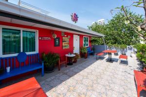 a red building with a patio with tables and chairs at BB House Phra Athit บีบี เฮ้าส์ พระอาทิตย์ in Bangkok