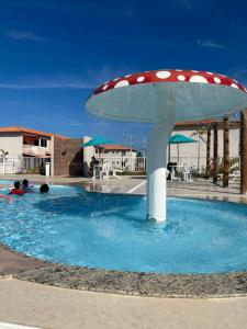 a swimming pool with a mushroom in the water at Ap à 600 metros da praia, um verdadeiro paraíso! in Barra dos Coqueiros