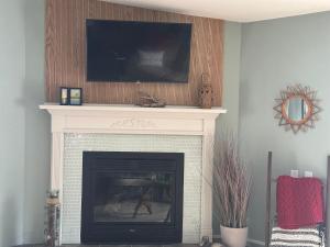 a living room with a fireplace with a tv above it at Legacy Lakehouse in Spicer