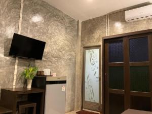 a room with a refrigerator and a tv on a wall at Rai Phuchat in Ban Pa Thon