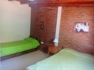 a bedroom with two beds and a brick wall at Nahian in Mina Clavero +38 photos
